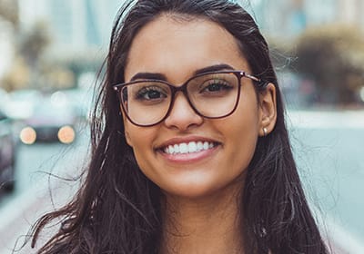 woman with glasses standing in street and smiling