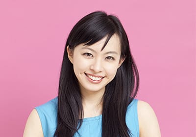 woman in front of pink backgorund smiling with dimples in her cheeks