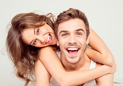 happy woman hugging happy man around neck from behind