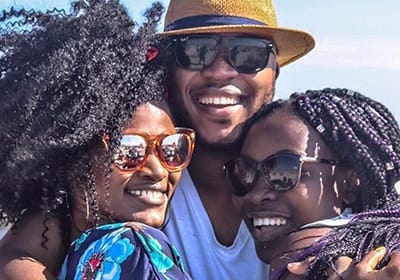 two women and one man holding each other as they have fun at the beach