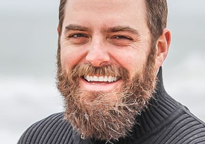 happy man with out of control beard standing near the ocean