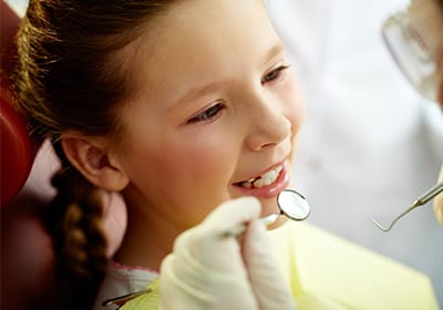 child sitting in dental chair receiving an exam