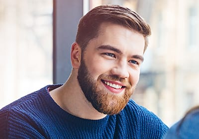 smiling man with beard listening to someone talk